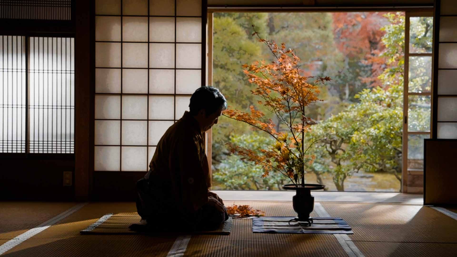 床の間に生けられた花と、和室に座す人物